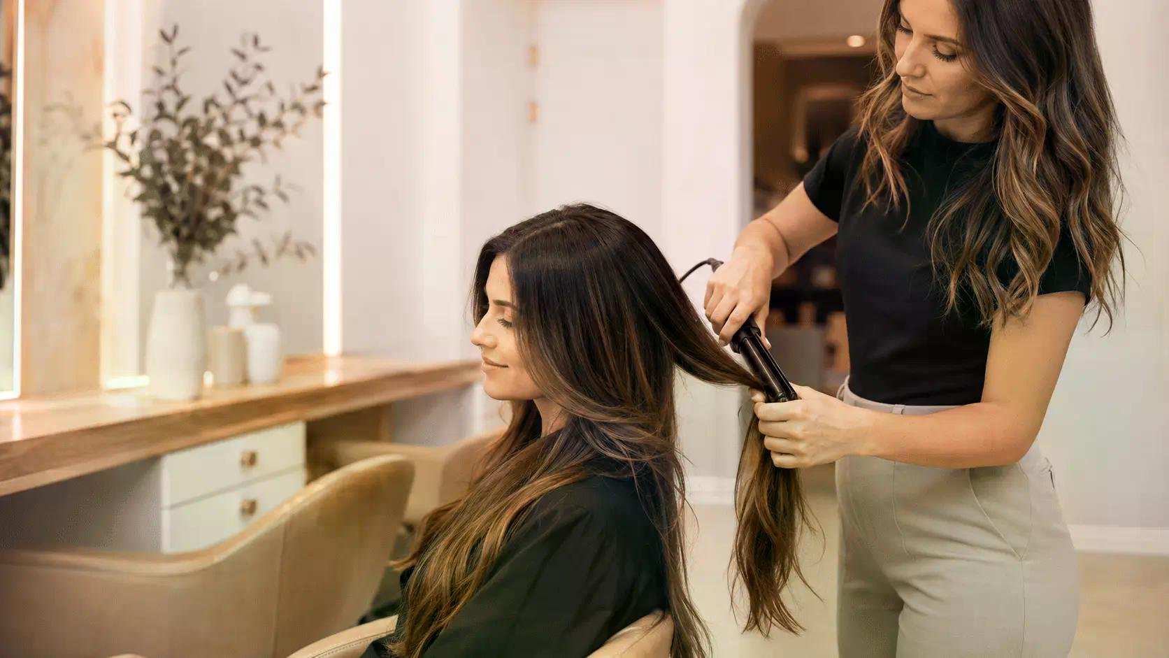 Coup de cheveux chez lisseur par une professionnelle, une cliente assise pendant que l’extension est posée section par section. Coup de cheveux chez lisseur par une professionnelle, une cliente assise pendant que l’extension est posée section par section.